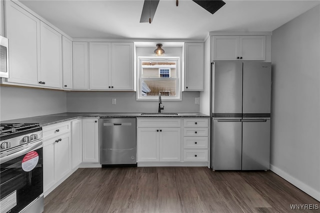 kitchen with stainless steel appliances, a sink, white cabinetry, a ceiling fan, and dark wood-style floors