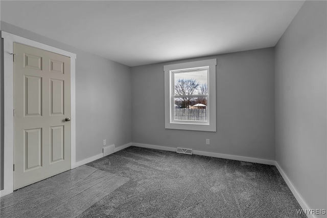 carpeted spare room featuring baseboards and visible vents