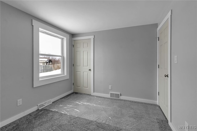 carpeted spare room with visible vents and baseboards