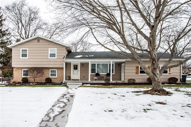 split level home featuring a porch and brick siding