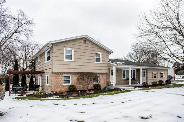 split level home featuring a porch, a pergola, and brick siding