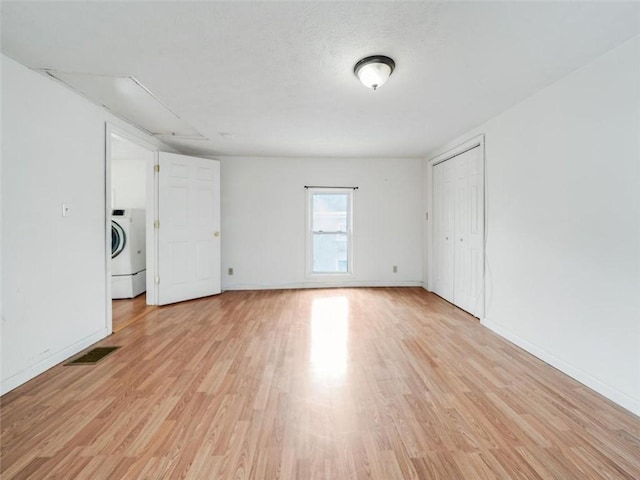 spare room with visible vents, baseboards, washer / clothes dryer, a textured ceiling, and light wood-type flooring