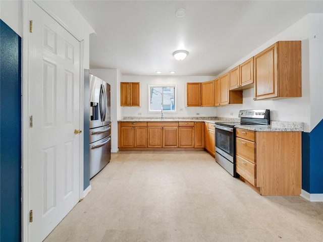 kitchen with baseboards, brown cabinetry, appliances with stainless steel finishes, light countertops, and a sink