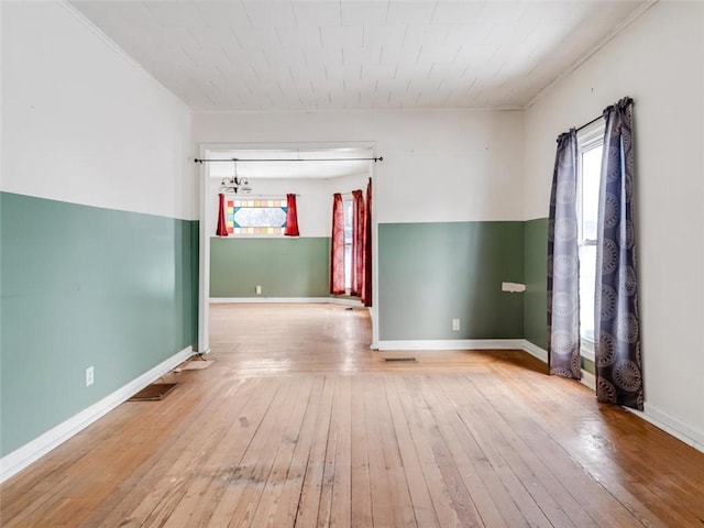 spare room featuring baseboards, wood-type flooring, and a healthy amount of sunlight