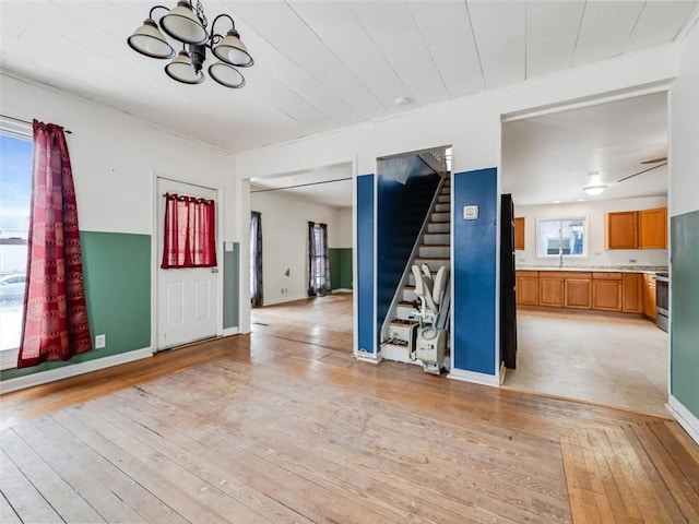 interior space featuring a notable chandelier, a sink, baseboards, stairway, and light wood finished floors