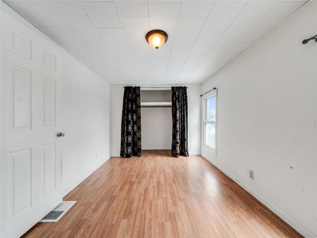 empty room with baseboards, visible vents, and light wood finished floors