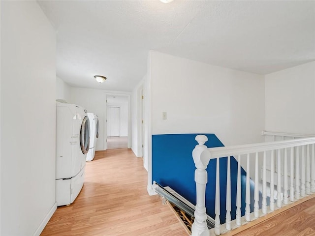 hallway with light wood-style flooring, baseboards, and separate washer and dryer