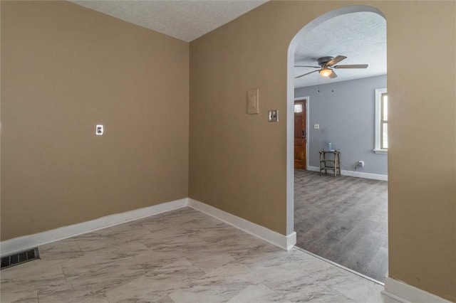 spare room with arched walkways, a textured ceiling, visible vents, baseboards, and marble finish floor