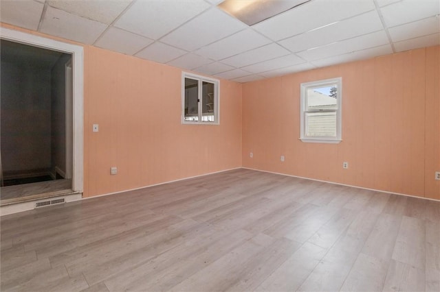 empty room featuring a paneled ceiling, visible vents, and wood finished floors