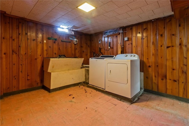 laundry area featuring laundry area, washing machine and dryer, wooden walls, and light floors