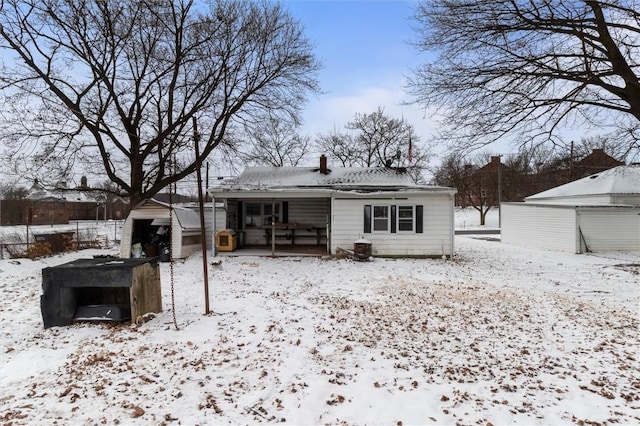 snow covered house with an outdoor structure and fence