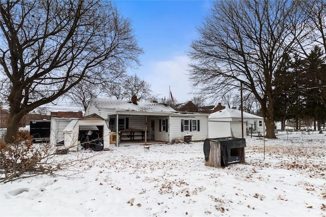 snow covered house featuring an outbuilding and a detached garage