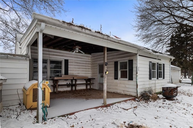 snow covered back of property featuring a ceiling fan and a patio