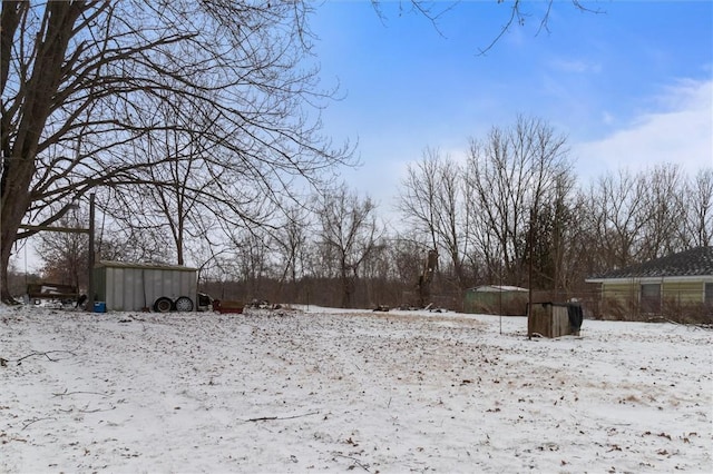 yard covered in snow featuring a storage unit and an outbuilding