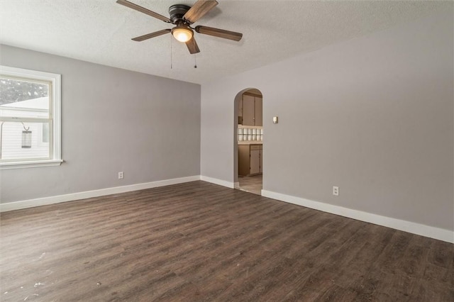 unfurnished room featuring baseboards, arched walkways, a ceiling fan, wood finished floors, and a textured ceiling