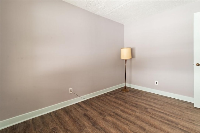 empty room featuring dark wood-type flooring and baseboards