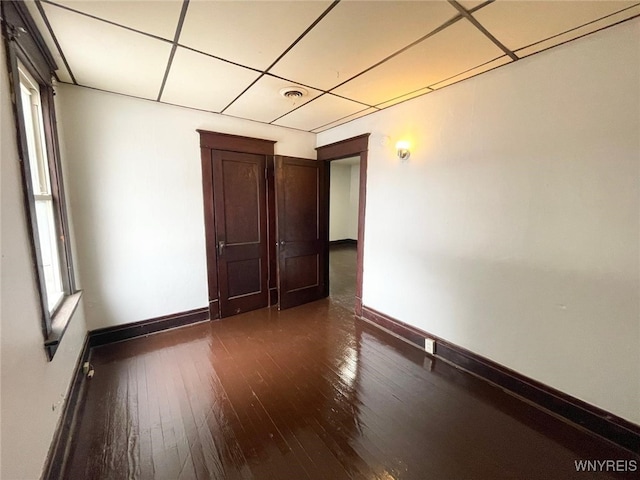 unfurnished room featuring baseboards, wood-type flooring, visible vents, and a drop ceiling