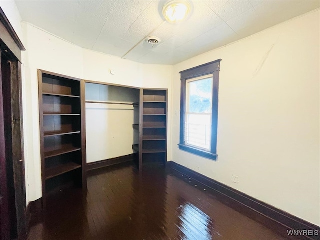 unfurnished bedroom with baseboards, visible vents, and hardwood / wood-style floors