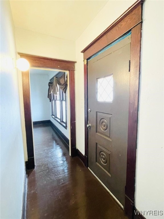 corridor featuring dark wood-style flooring and baseboards