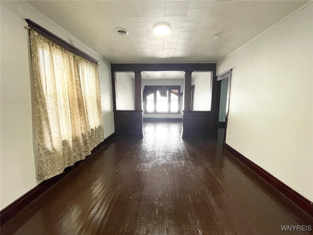 corridor with hardwood / wood-style floors, visible vents, and baseboards