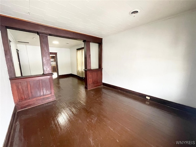 unfurnished room with dark wood-type flooring, visible vents, and baseboards