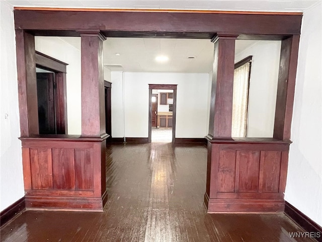 corridor with ornate columns, baseboards, and hardwood / wood-style floors