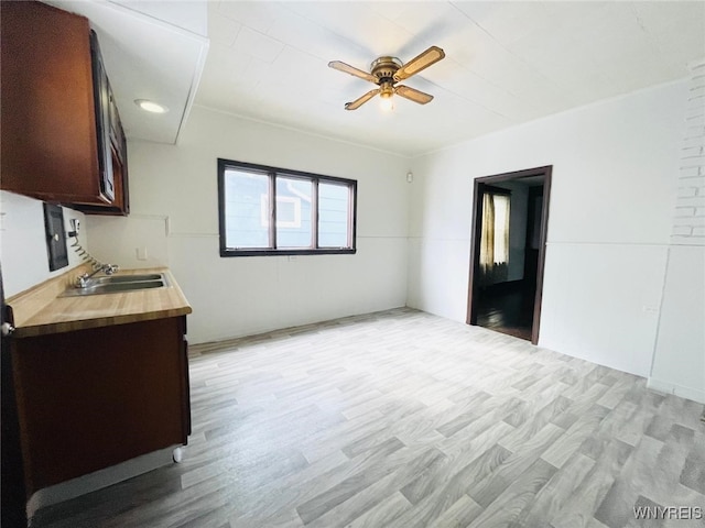 kitchen featuring dark brown cabinets, light wood-style flooring, ceiling fan, and a sink