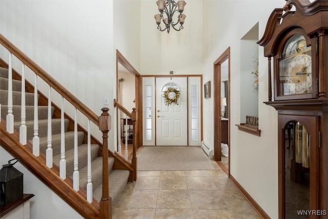 foyer featuring a notable chandelier, light tile patterned floors, baseboard heating, a high ceiling, and baseboards