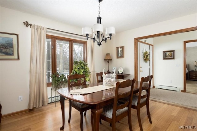 dining space featuring a baseboard radiator, light wood-style flooring, baseboard heating, and an inviting chandelier