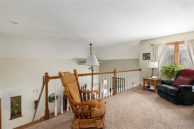 sitting room featuring a textured ceiling, carpet, and an upstairs landing