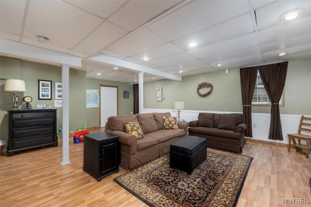 living area featuring light wood-style floors, a paneled ceiling, wainscoting, and recessed lighting