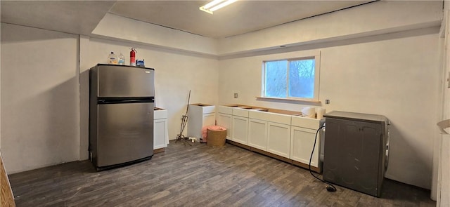 kitchen featuring a raised ceiling, dark wood finished floors, freestanding refrigerator, and white cabinets