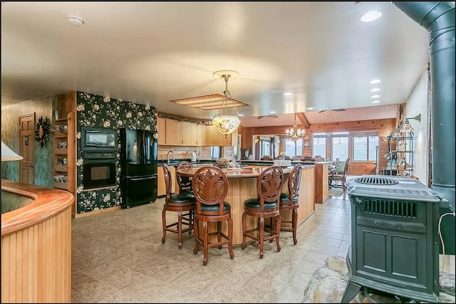 kitchen featuring a breakfast bar, pendant lighting, a sink, and black appliances