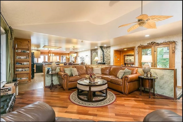 living room with ceiling fan, wood finished floors, vaulted ceiling, a raised ceiling, and wallpapered walls