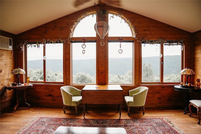 sunroom / solarium with plenty of natural light, a wall unit AC, and vaulted ceiling