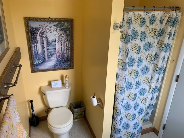 bathroom featuring a shower with curtain, baseboards, and toilet