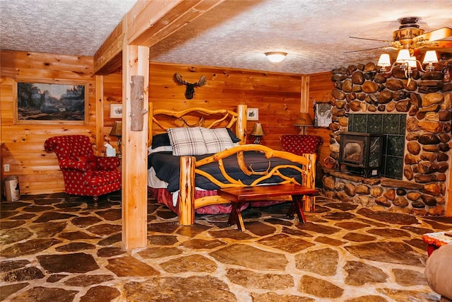 bedroom featuring wooden walls, stone floors, and a textured ceiling