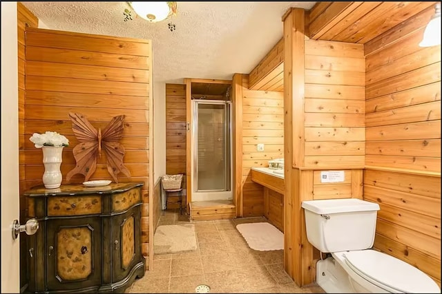 bathroom featuring toilet, a textured ceiling, vanity, wood walls, and a shower stall