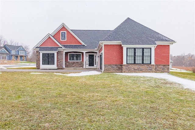 view of front of home featuring a front yard, stone siding, and roof with shingles