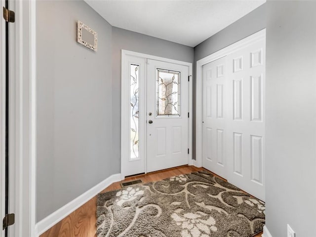 foyer featuring wood finished floors, visible vents, and baseboards