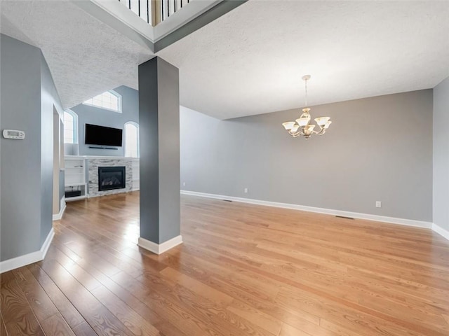 unfurnished living room featuring light wood-type flooring, baseboards, and a chandelier