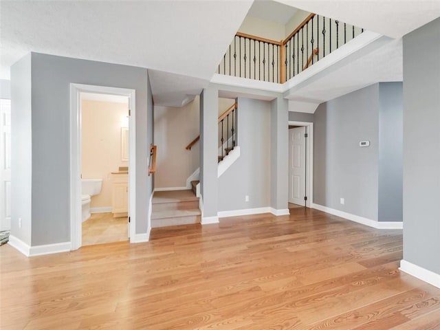 interior space featuring baseboards, stairway, a towering ceiling, and light wood-style floors