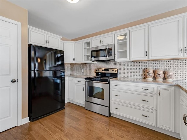 kitchen featuring backsplash, appliances with stainless steel finishes, glass insert cabinets, white cabinetry, and light wood-type flooring