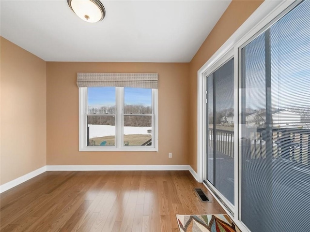 spare room featuring wood finished floors, visible vents, and baseboards