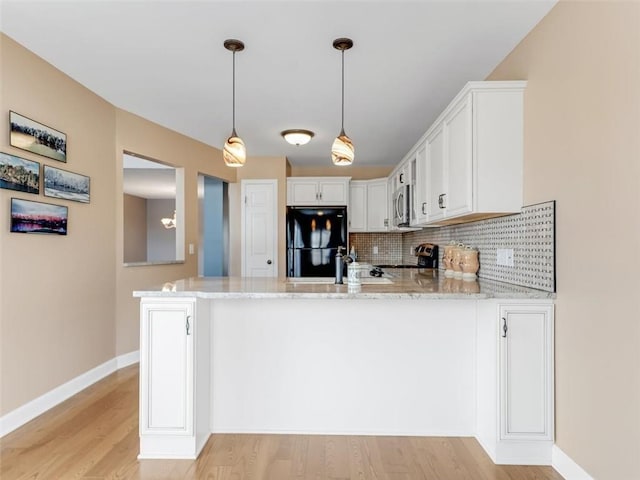 kitchen featuring a peninsula, tasteful backsplash, appliances with stainless steel finishes, and light stone counters