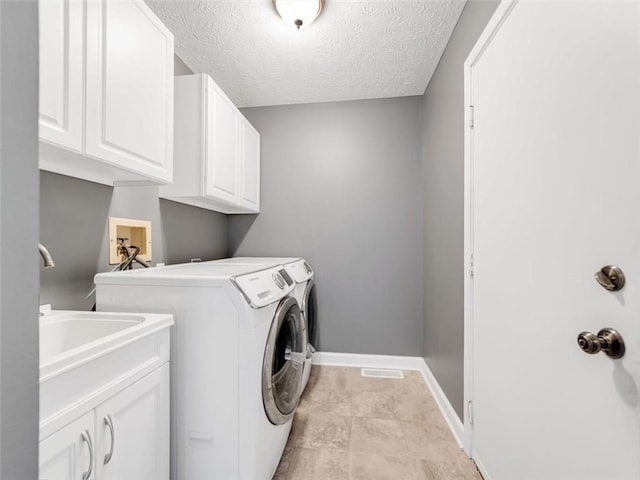 laundry area featuring baseboards, a textured ceiling, cabinet space, and washer and dryer