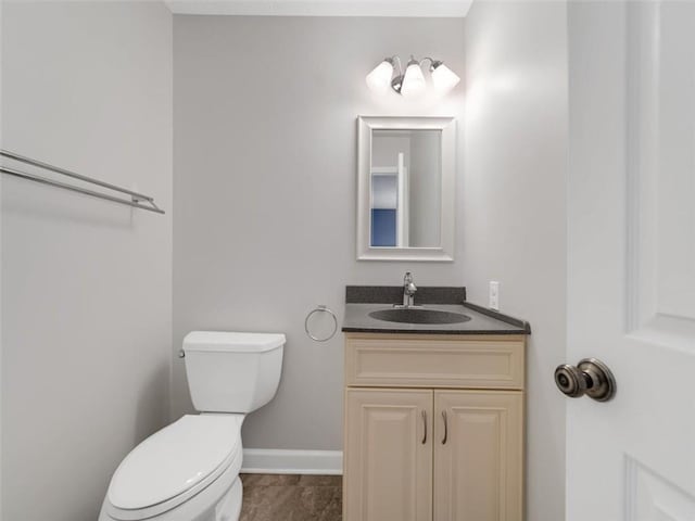 half bath with vanity, toilet, and baseboards