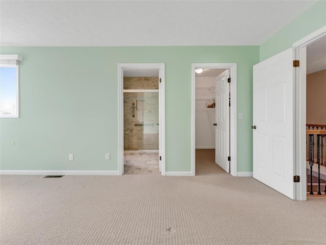 unfurnished bedroom with a spacious closet, carpet floors, visible vents, and baseboards