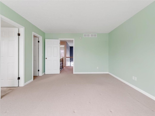 spare room with carpet floors, baseboards, and visible vents