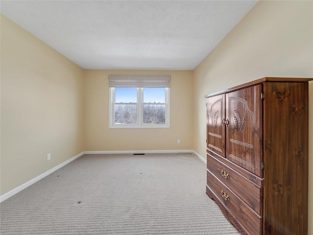 unfurnished bedroom with light carpet, baseboards, and a textured ceiling